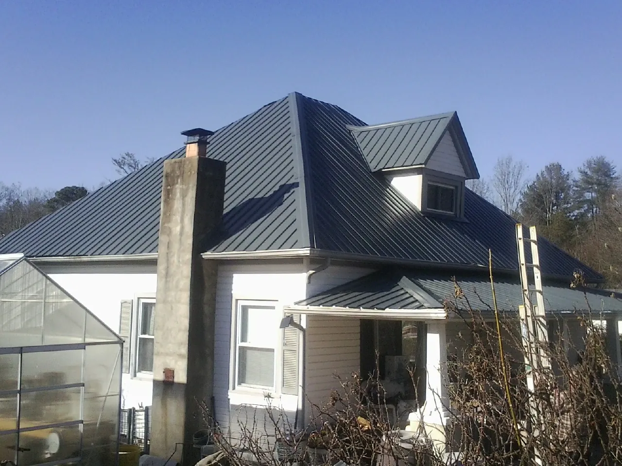 Dark blue standing seam metal roof on a white farmhouse with dormer — Slate & Tile Roof Repair by Roofing Brothers in Cadogan