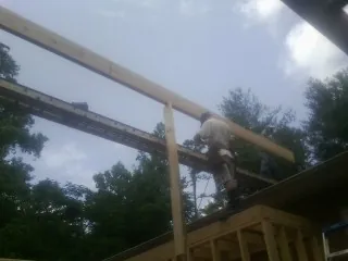 Carpenter setting a ridge beam over a new addition frame — Ice Dam Removal by Roofing Brothers in Cadogan