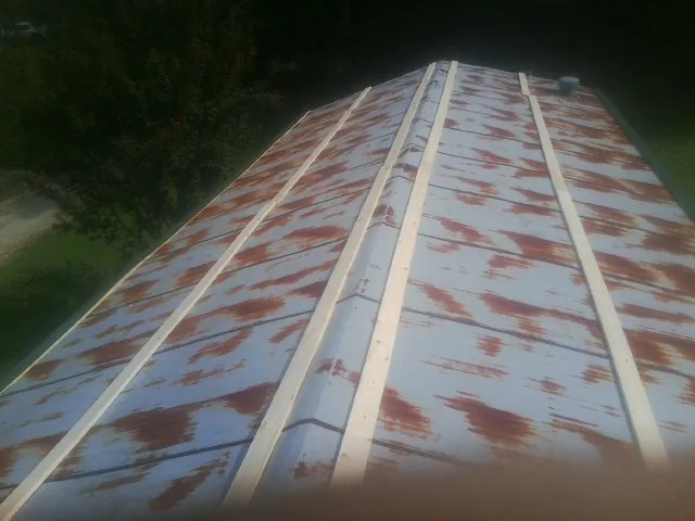 Rusted metal roof panels with new wood purlins before replacement — Storm Damage Roof Repair in Cadogan by Roofing Brothers