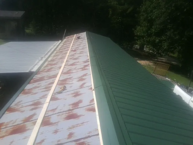 Old rusted panels beside newly installed green metal roofing — Wind Damage Roof Repair by Roofing Brothers in Cadogan