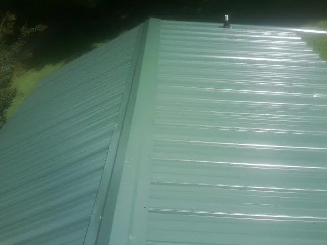 New green metal panels meeting at the ridge of a roof — Flat Roof Repair work by our crew in Cadogan