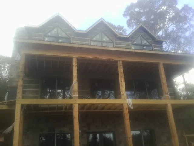 Dormers and porch framing on a large log home under construction — Roof Coating work by our crew in Cadogan