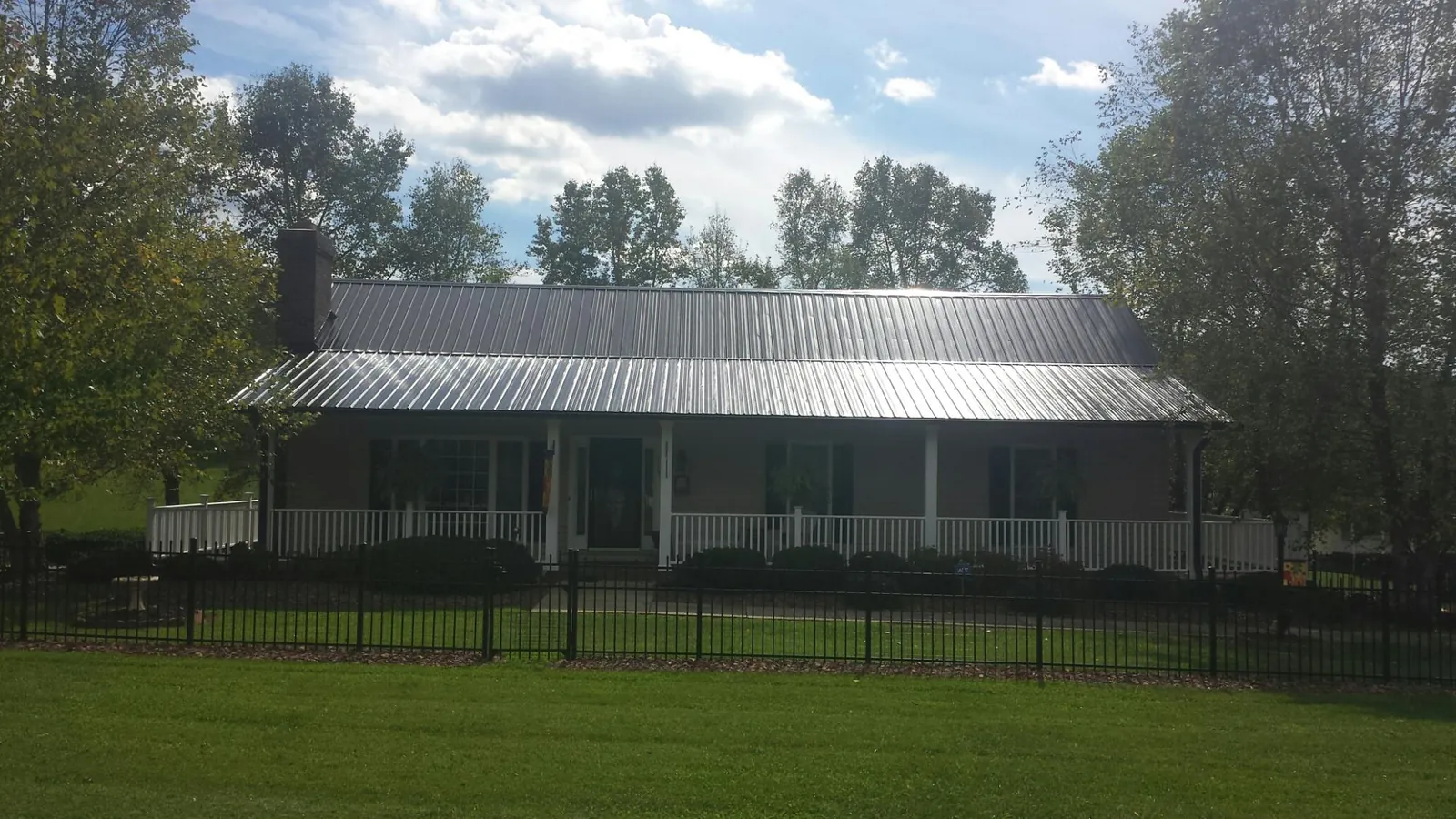 Gray metal roof on a brick ranch with a full width front porch — Gutter Guard Installation work by our crew in Cadogan