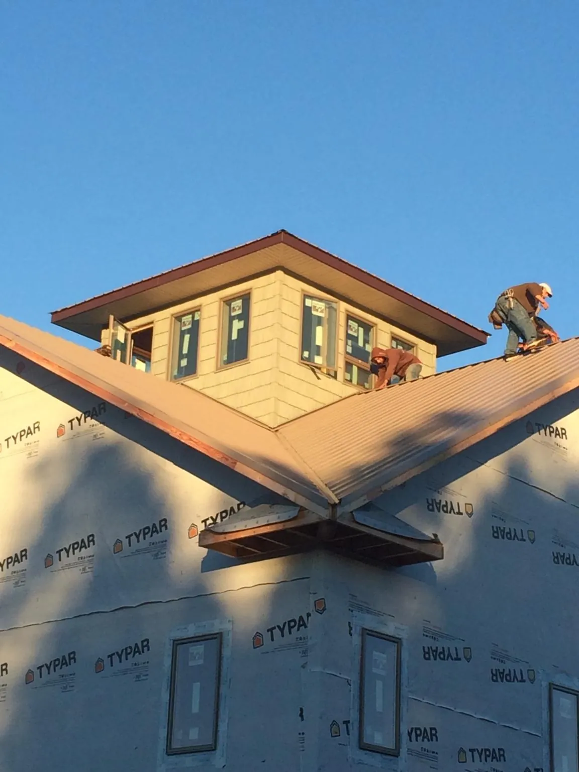 Roofers working around a rooftop cupola on a new metal roof at sunset — Roof Waterproofing in Cadogan by Roofing Brothers